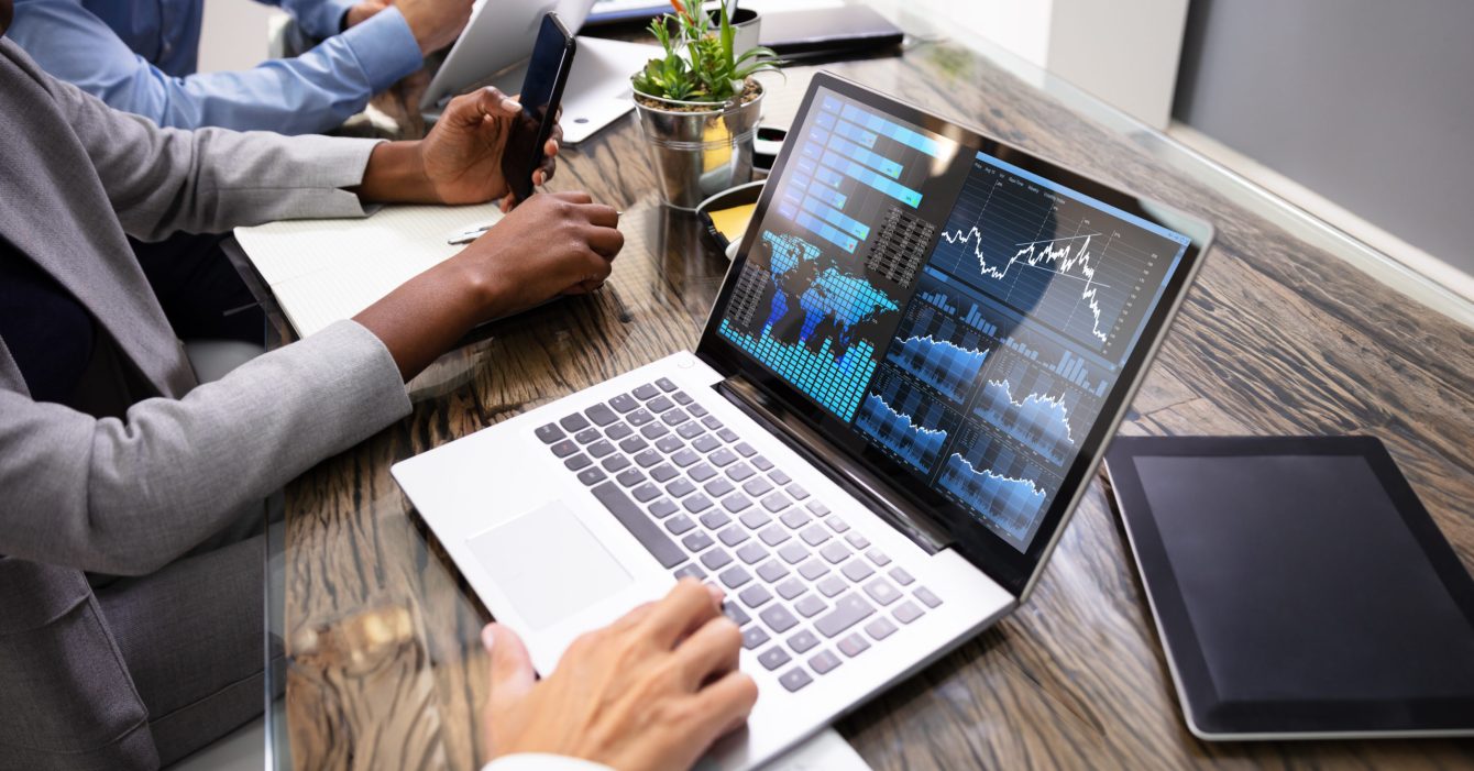 Group Of Businesspeople Examining Graph On Computer Group Of Businesspeople Examining Graph On Computer