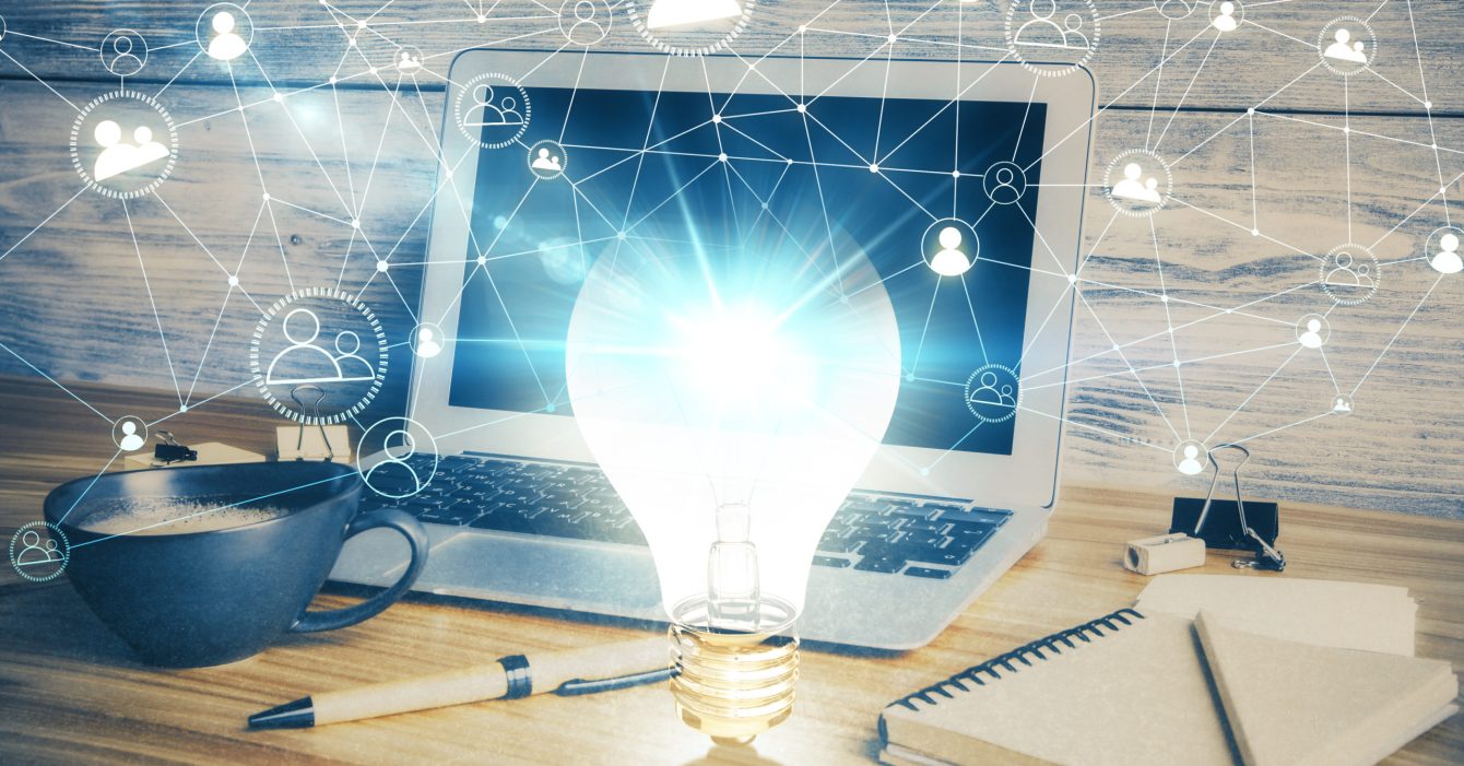 Computer on desktop in office with bulb icon hologram. Double exposure. Concept of idea. Computer on desktop in office with bulb icon hologram. Double exposure. Concept of idea.